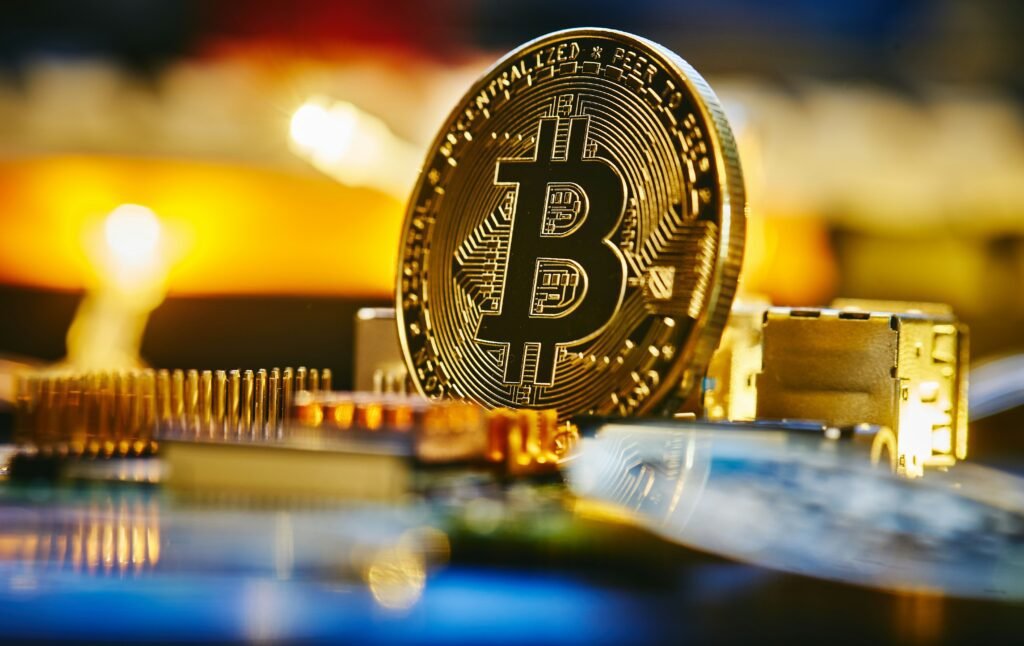Close-up of a Bitcoin coin with a blurred background of computer components, symbolizing cryptocurrency and blockchain technology.