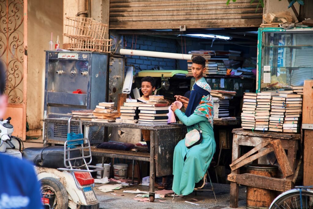 Street scene with people sitting at a table surrounded by stacks of books