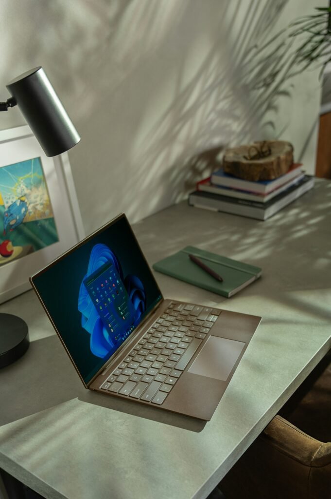 Open laptop on a desk, sunlight casting shadows, symbolizing modern technology and digital workspaces.