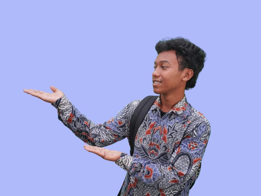 Person in patterned shirt gesturing with both hands against a blue background