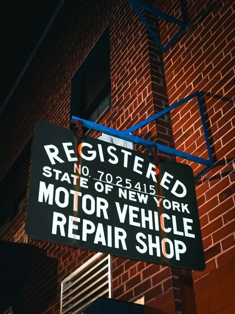 NYC motor vehicle repair shop sign on brick wall at night