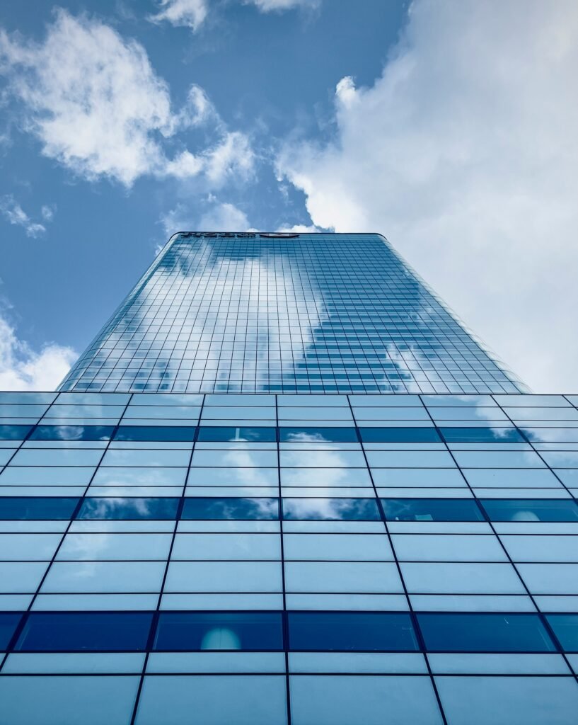 Modern glass skyscraper reflecting clouds and blue sky, symbolizing growth and technology in the crypto industry.