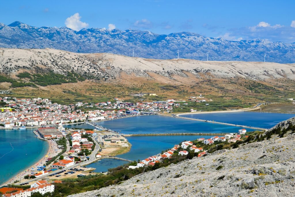 Scenic view of coastal town surrounded by mountains and wind turbines