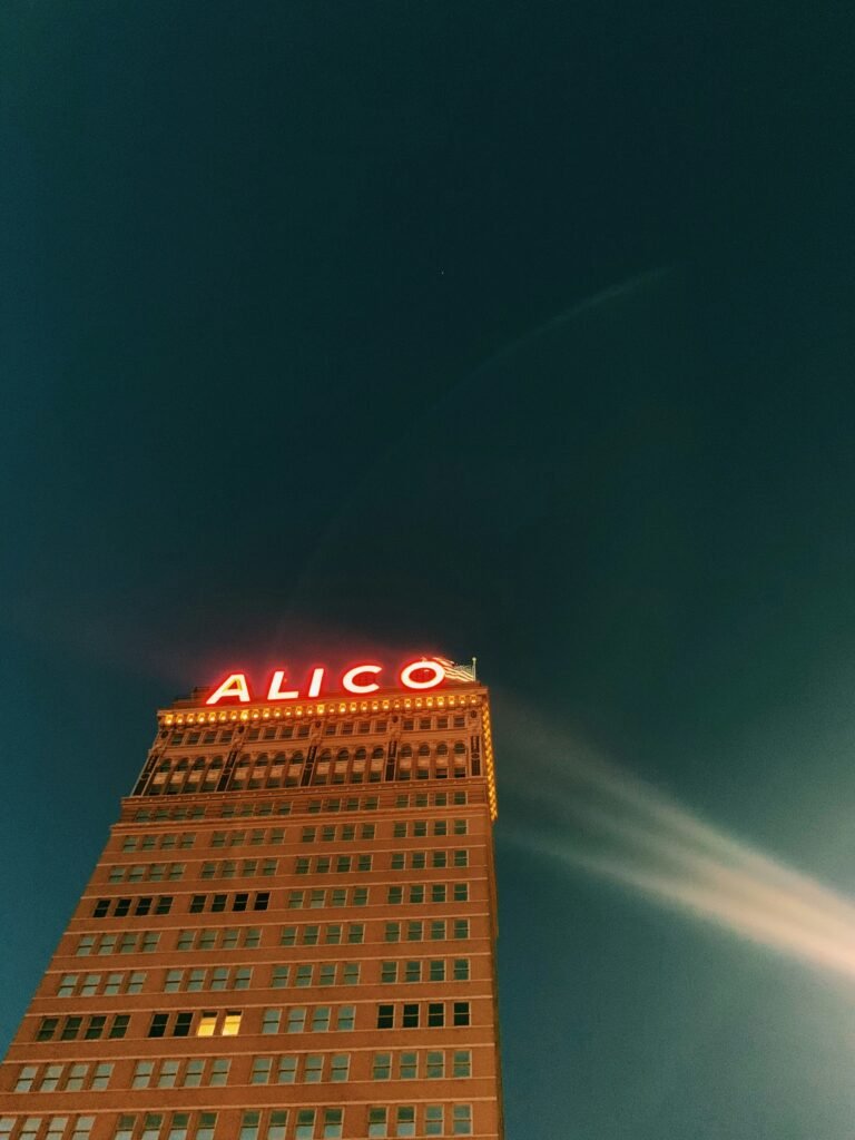 Night view of a tall building with 'ALICO' sign illuminated at the top.