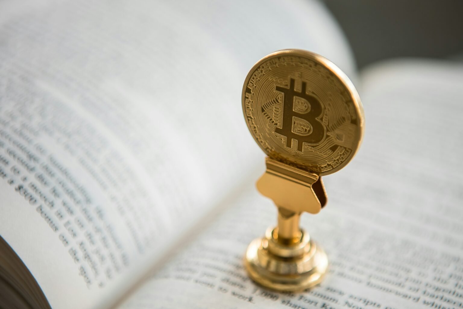 Gold Bitcoin trophy resting on an open book, symbolizing cryptocurrency knowledge
