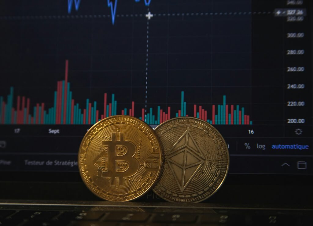 Bitcoin and Ethereum coins in front of financial market chart on screen