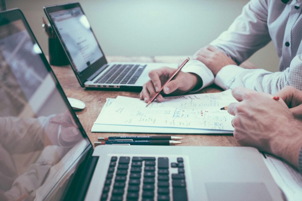 Two people discussing crypto investments at a desk with laptops and documents